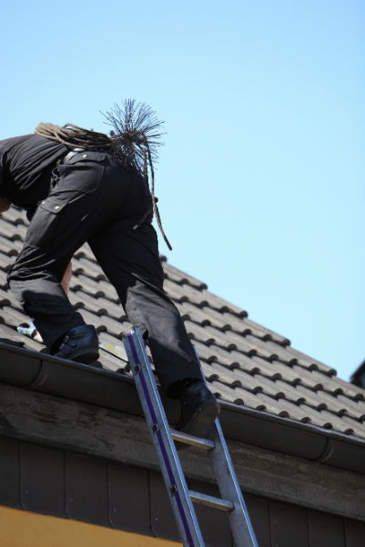 Technician on a Ladder Sweeping Chimney