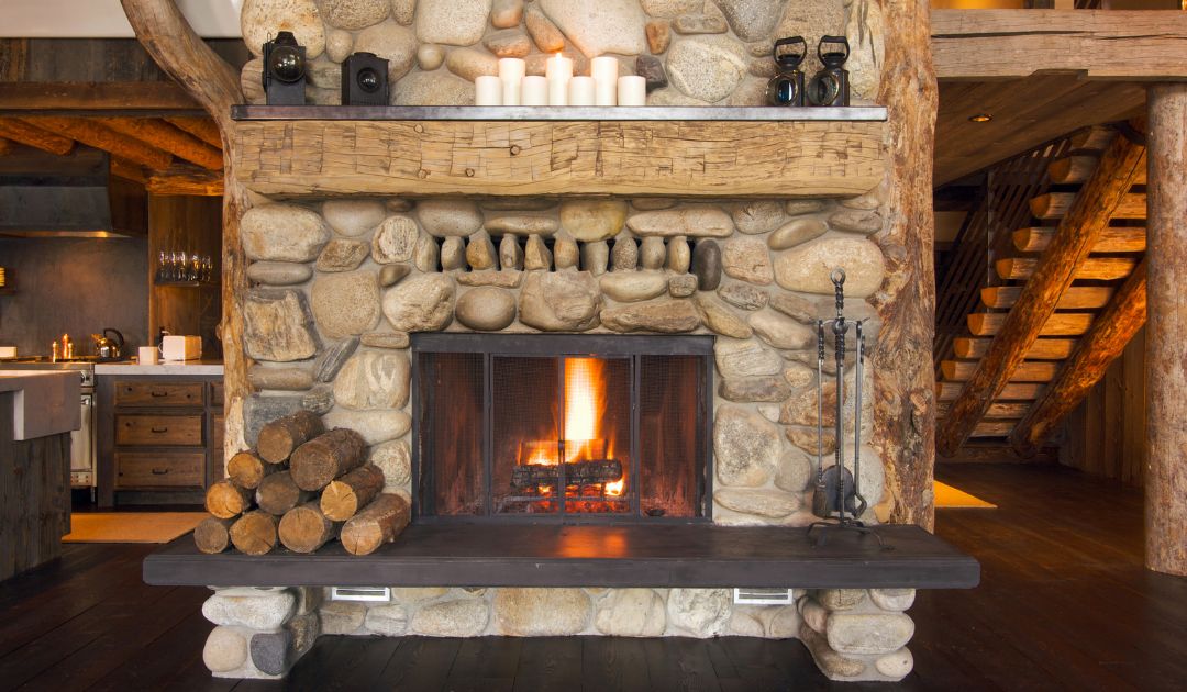 large stone wood fireplace with a pile of logs next to it in a cabin-type setting